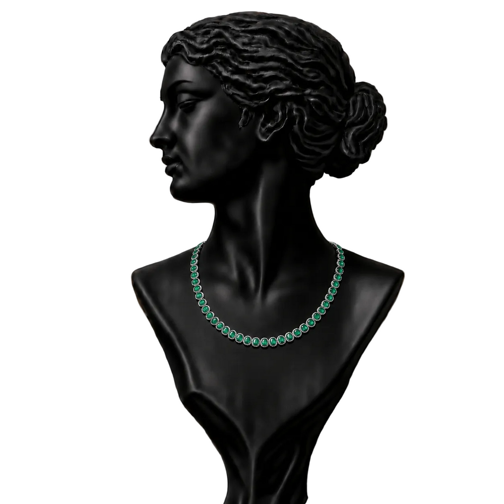 A black classical-style bust display wearing a necklace of round green gemstones.