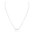 A delicate rose gold chain necklace featuring a small central cluster of iridescent, pearl-like beads, displayed on a clean white background with a soft reflection.