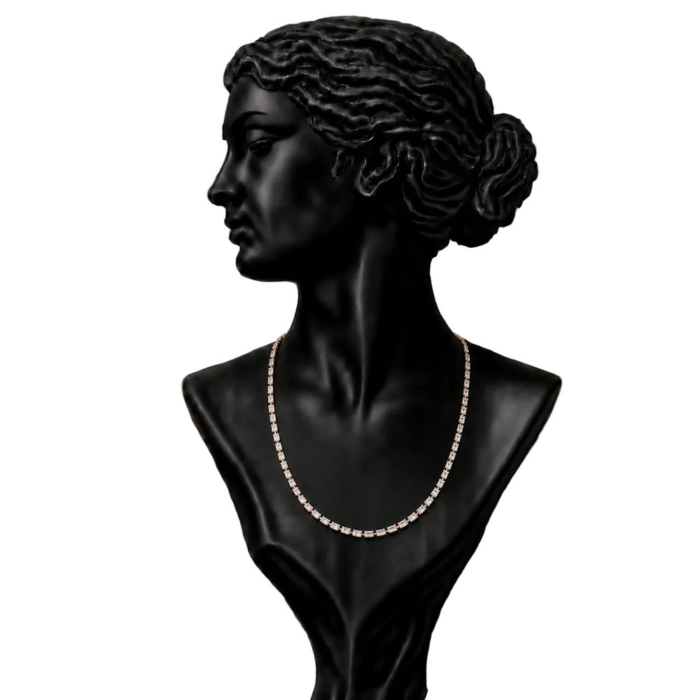 A black mannequin bust wearing a delicate gold-toned chain necklace, 